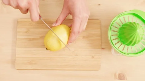 Woman's hands cutting and squeezing lemon on wooden table shot from above Stock Footage 121295707