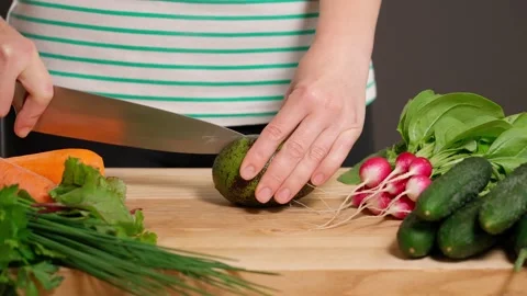 Woman's hands cutting avocado in two halves and vegetables Stock Footage 155432596