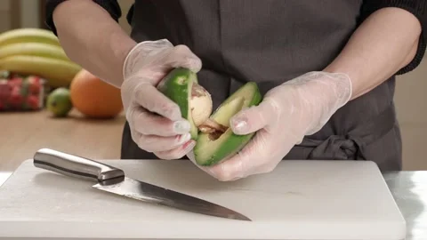 Woman's hands cutting avocado in two halves and vegetables Stock Footage 155433114