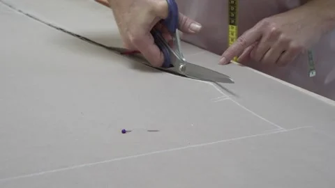 Woman's hands cutting a beige fabric with scissors on table in atelier Video stock 157246953