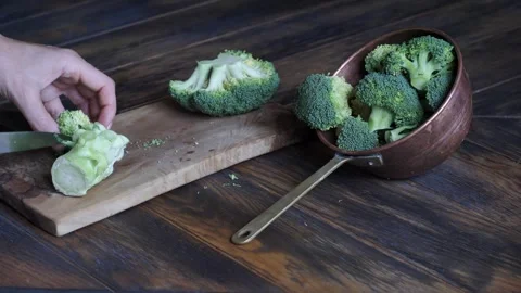 Woman's hands cutting broccoli cabbage on cutting board with small knife Stock Footage 247729328
