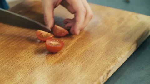Woman's hands cutting the cherry tomatoes into half pieces with chefs knife on Stock Footage 136114212