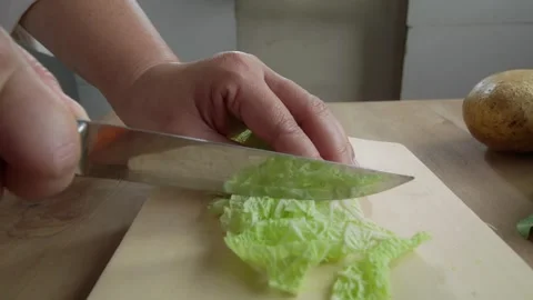 Woman's hands cutting chinese cabbage on a cutting board Stock Footage 329684359