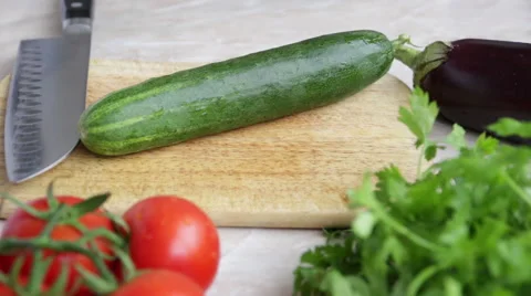 Woman's hands cutting cucumber, behind fresh vegetables. Video stock 51674047
