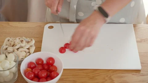 Woman's hands cutting fresh cherry tomatoes for a homemade pizza or pinsa Stock Footage 315670973