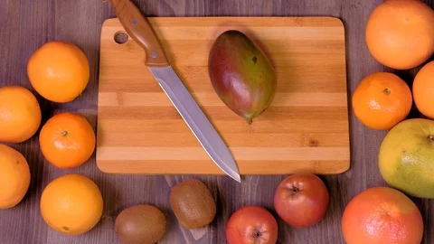 Woman's hands cutting fresh mango on kitchen Stock Footage 123356514