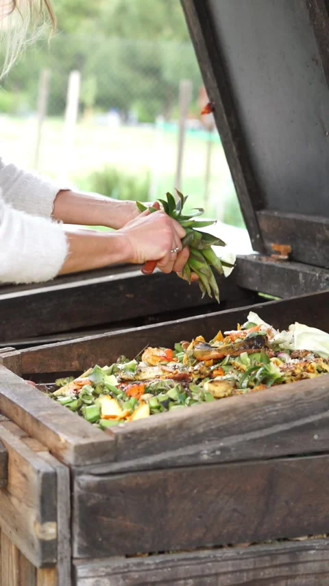 Woman's hands cutting leftover fruit and pouring it into a garden compost Stock Footage 275144227