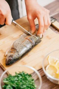 Woman's hands cutting raw fish. Stock Photos