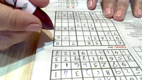 Woman's hands deciphering a gold level Sudoku with pen and paper Stock Footage 252399568
