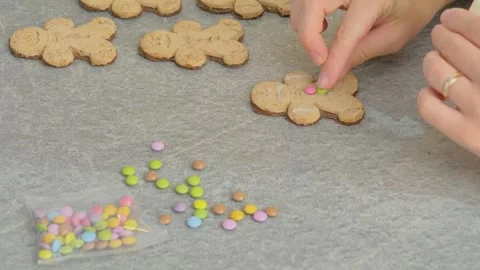 Woman's hands decorating a gingerbread man-shaped Christmas cake with white Stock Footage 256442206