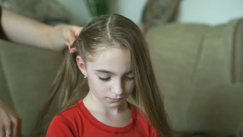 Woman's hands do hairstyle for her little daughter. A woman is braiding hair for Stock Footage 90607953