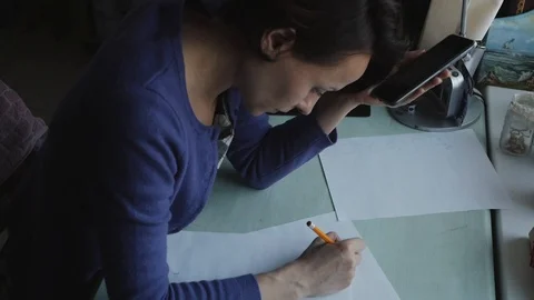 Woman's hands drawing on the white sheet of paper on the wood desk. Stock Footage 104288001