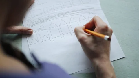 Woman's hands drawing on the white sheet of paper on the wood desk. 動画素材 104412122
