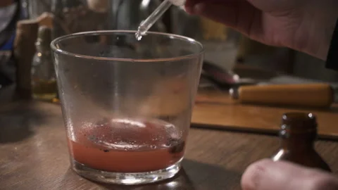 Woman's hands drip some substance into the glass with red liquid Stock Footage 89674942