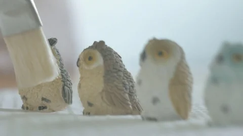 Womans hands dusting tiny ceramic owls using paint brush. Not B&amp;W Vidéo 72868756