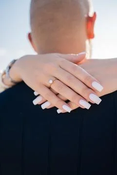 Woman's hands with an engagement ring resting on her fiance's shoulder Stock Photos
