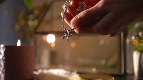 Woman's hands examining a silver balloon dog charm bracelet Stock Footage 328006630