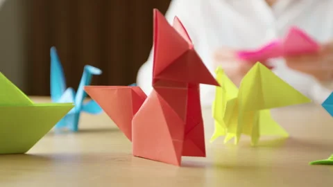 Woman's hands folding origami colored paper on table. Stock-Footage 296903175