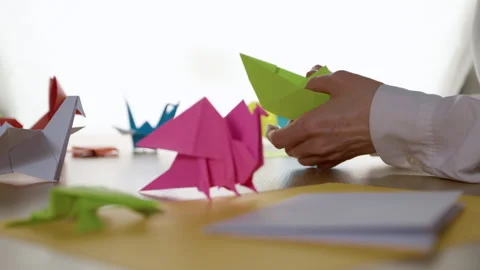 Woman's hands folding origami colored paper on table. Hobby, handmade  Stock Footage 296903381