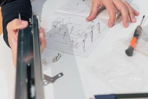 Woman's hands following instructions for assembling a piece of furniture Stock Photos