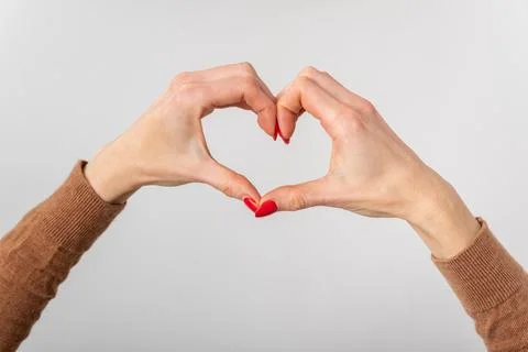 Woman's hands forming a heart shape with red fingernails, close up studio s.. Stock Photos