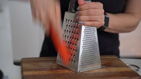 Woman's hands grates fresh raw orange carrot on big metal grater for summer Stock Footage 102217514