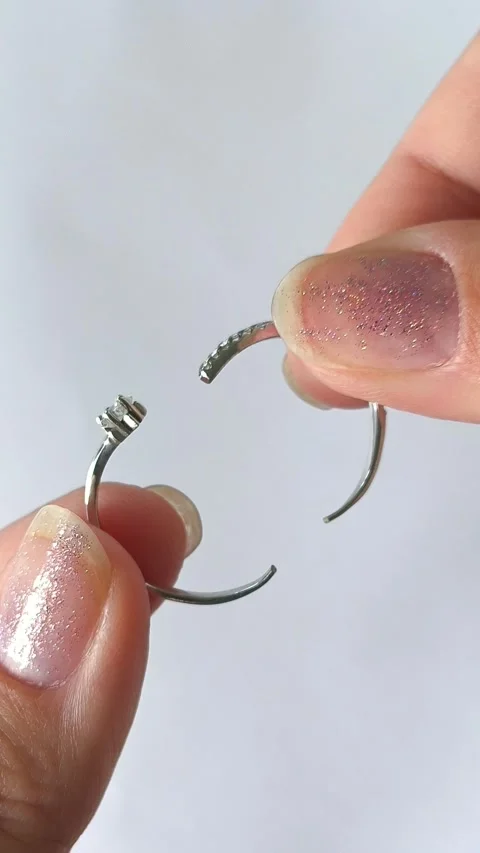 A womans hands hold a broken silver ring on a white background. Broken jewelry Stock Footage 313979669