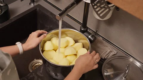 A woman's hands hold a pot under a faucet, filling it with tap water Stock Footage 315403805