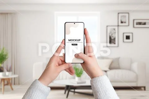 Woman's hands hold a smartphone mockup in a living room interior Plantilla PSD