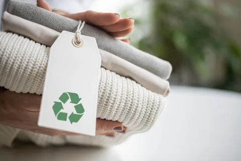 Woman's hands hold a stack of clean neat knitted clothes with a label with a Stock Photos