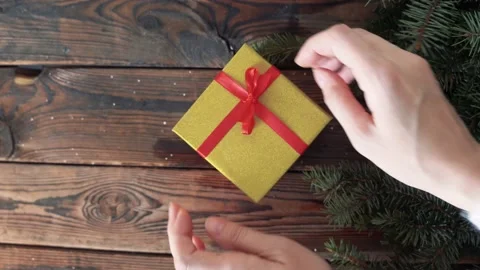 Woman's hands holding a box with a gift in her hands and puts on a wood table Stock Footage 140808647