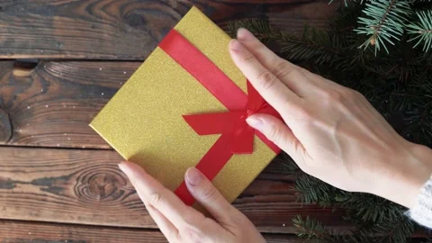 Woman's hands holding a box with a gift in her hands and puts on a wood table Stock Footage 140808684