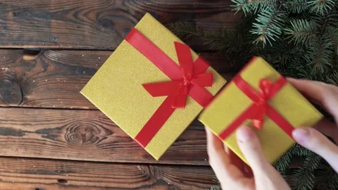 Woman's hands holding a box with a gift in her hands and puts on a wood table Stock Footage 140808714