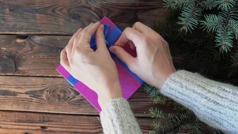 Woman's hands holding a box with a gift in her hands and puts on a wood table Stock Footage 140808752