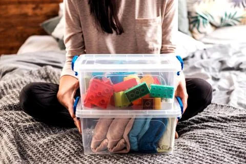 Woman's hands holding boxes with blocks and clothing. Stock Photos