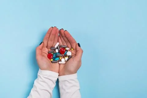 Woman's hands holding a different tablets and pills over blue Stock Photos