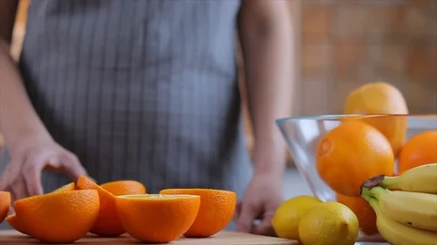 Woman's hands is holding a orange half and making juice Stock Footage 104800700