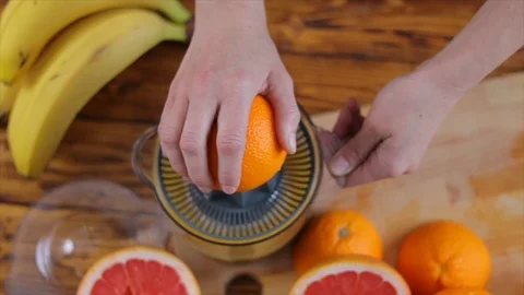 Woman's hands is holding a orange half and making juice Stock Footage 104801323