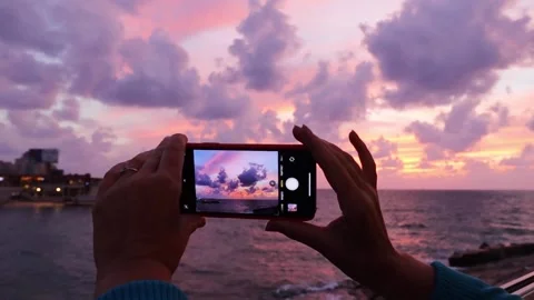 Woman's hands holding smartphone and shooting sunset sky over the sea Stock Footage 252297066