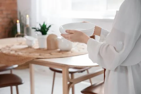 Womans hands holding stack of clean white ceramic bowls in a bright dining ro Stock Photos