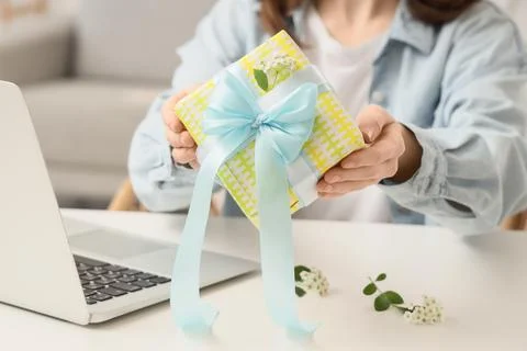 Womans hands holding a yellow patterned gift box with a light blue ribbon bow Stock Photos