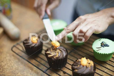 Womans Hands Icing Cup Cakes On Cooling Rack