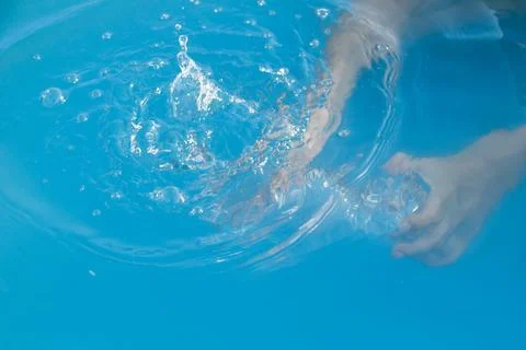 Woman's hands inside the pool with water filling water bottle Stock Photos
