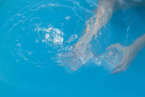 Woman's hands inside the pool with water filling water bottle Stock Photos