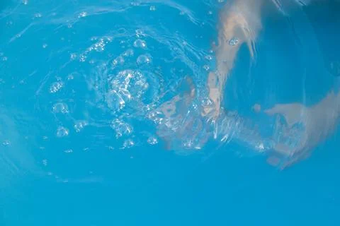 Woman's hands inside the pool with water filling water bottle Stock Photos