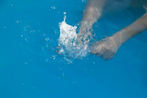 Woman's hands inside the pool with water filling water bottle Stock Photos