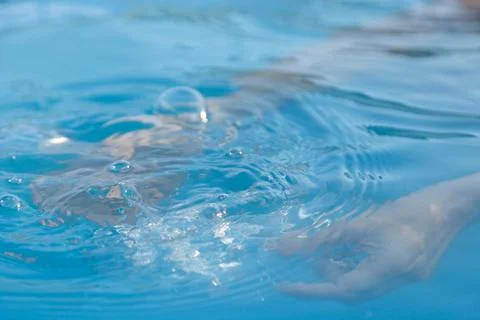 Woman's hands inside the pool with water filling water bottle Stock Photos