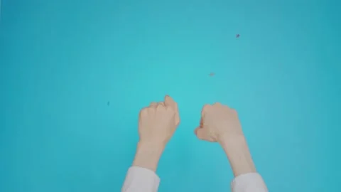 Womans hands isolated on blue background with confetti falls. Woman raising Video stock 131060219