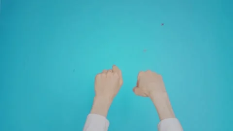 Womans hands isolated on blue background with confetti falls. Woman raising Stock Footage 131062173