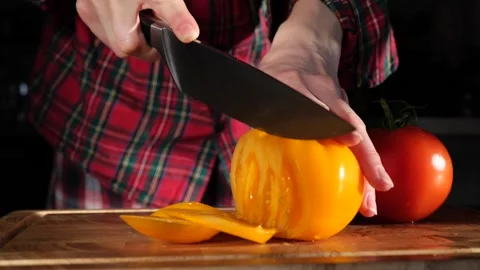 Woman's hands in kitchen cutting fresh tomato on wooden cutting board Stock-Footage 147934883